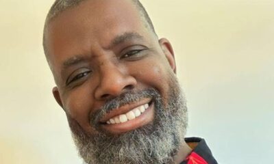 Rosto de homem negro sorridente com barba e cabelo grisalho