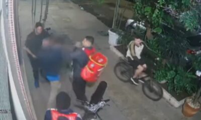 Gravação granulada de câmera de segurança mostrando pessoas durante uma briga na rua