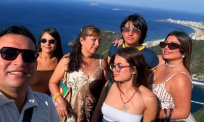 Grupo de seis pessoas sorrindo em selfie com vista panorâmica do Rio de Janeiro