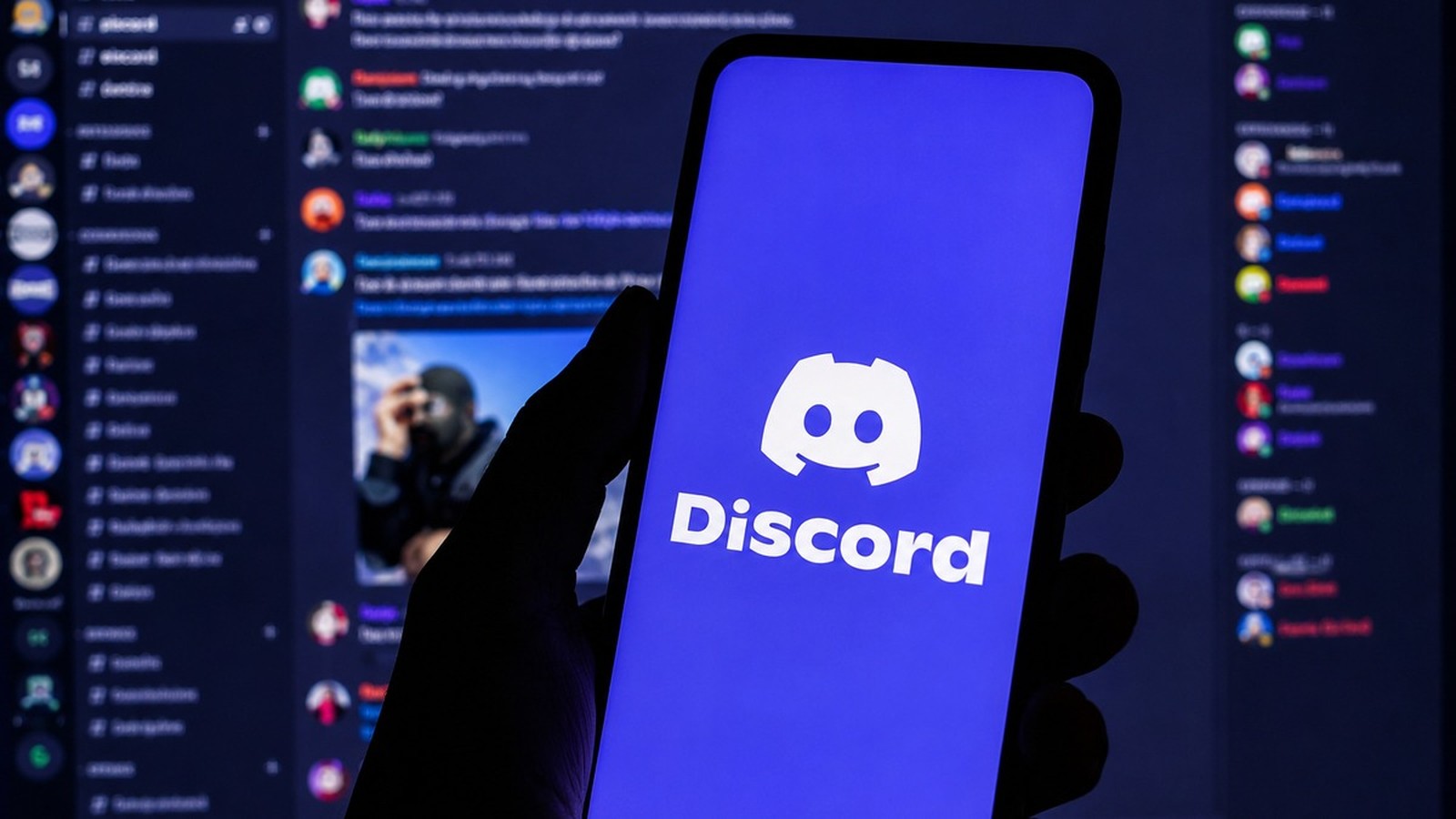 Mão segura smartphone com logo Discord na tela, fundo com interface da plataforma borrada