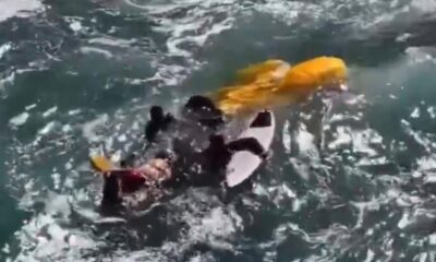Pessoa em wetsuit na água com equipamento branco e objeto laranja flutuando
