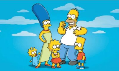 Desenho animado da família Simpson completa: Marge, Homer, Bart, Lisa e Maggie sorrindo contra céu azul