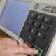 Mão pressiona botão "CONFIRMA" em urna eletrônica da Justiça Eleitoral, com teclado numérico