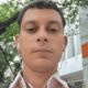 Homem com fones de ouvido brancos, em frente a edifício com as letras 'It' e '207'