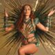 Cantora Anitta em fantasia dourada e verde com coroa e fundo de raios brilhantes