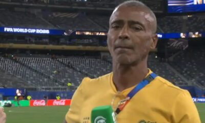 Homem de camisa amarela Romário com microfone verde em estádio, telão 'FIFA World Cup'