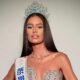Mulher jovem com coroa, faixa de Miss Brasil e vestido brilhante posa para foto