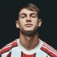 Retrato de homem jovem com cabelo escuro vestindo camisa listrada de futebol