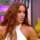 Anitta, com cabelos castanhos longos e blusa branca, fala em entrevista