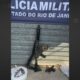 Fuzil camuflado, duas pistolas, sacolas com entorpecentes e banner da Polícia Militar