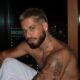 Zé Felipe sem camisa, com barba e colar, vista noturna ao fundo
