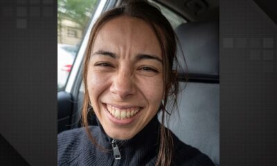 Mulher de cabelos castanhos rindo intensamente com olhos apertados dentro de um carro