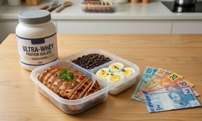 Refeição com frango, feijão e ovos ao lado de pote de whey protein e notas de reais, representando economia na alimentação proteica