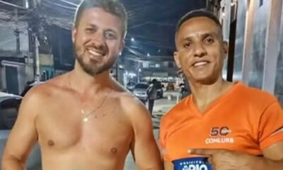 Dois homens sorrindo, um sem camisa e outro de camiseta laranja 5C Comlurb na rua