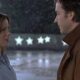 Perfis de Kate Beckinsale e John Cusack se encarando sob neve e estrelas iluminadas