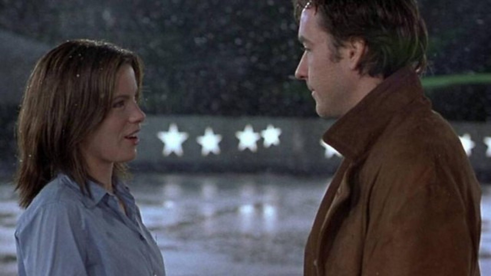 Perfis de Kate Beckinsale e John Cusack se encarando sob neve e estrelas iluminadas