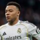 Kylian Mbappé em camisa branca do Real Madrid com escudo e logotipo Adidas