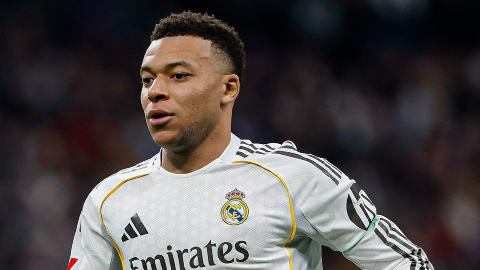 Kylian Mbappé em camisa branca do Real Madrid com escudo e logotipo Adidas