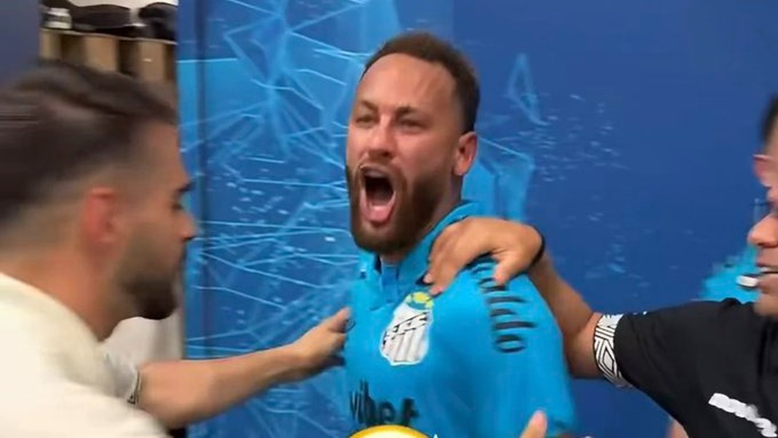 Jogador Neymar com boca aberta, camisa azul de futebol, braços de duas pessoas