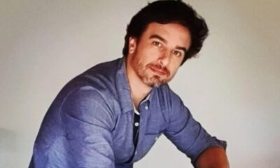 Homem de cabelo e barba escura, camisa azul, olhando para câmera