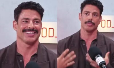 Cauã Reymond com bigode em podcast, sorrindo e gesticulando, fundo com logo "POD_i"