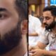Nuri Eftekhari, barbudo, em close-up e sentado com avental em set de cozinha