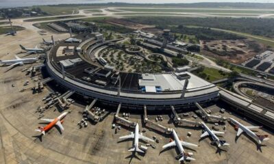 Vista aérea de um terminal de aeroporto circular com vários aviões estacionados em pátio