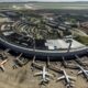 Vista aérea de um terminal de aeroporto circular com vários aviões estacionados em pátio