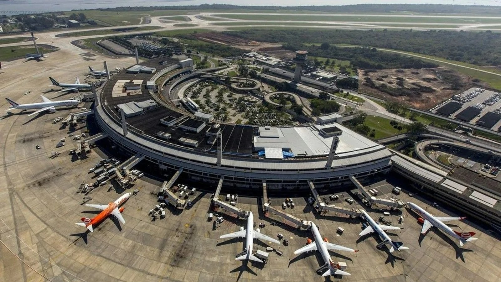 Vista aérea de um terminal de aeroporto circular com vários aviões estacionados em pátio