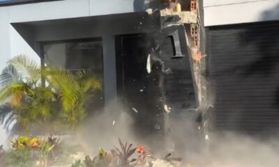 Exterior de casa moderna danificada com poeira e escombros, número 1 visível na parede preta