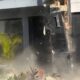 Exterior de casa moderna danificada com poeira e escombros, número 1 visível na parede preta