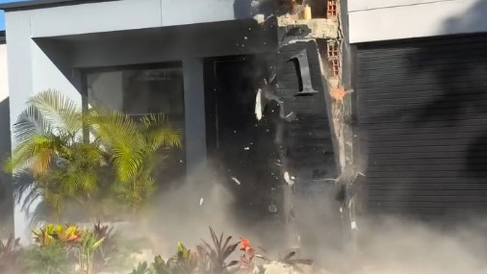 Exterior de casa moderna danificada com poeira e escombros, número 1 visível na parede preta