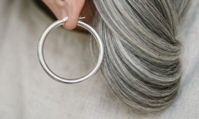 Argola prateada ao lado de uma mecha de cabelo grisalho, destacando a combinação entre o brilho do metal e os fios claros.