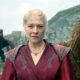 Emma D'Arcy como Rhaenyra Targaryen em traje vermelho com dois dragões ao fundo