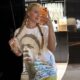Mulher loira de tranças posa para selfie no espelho, vestindo camiseta branca estampada