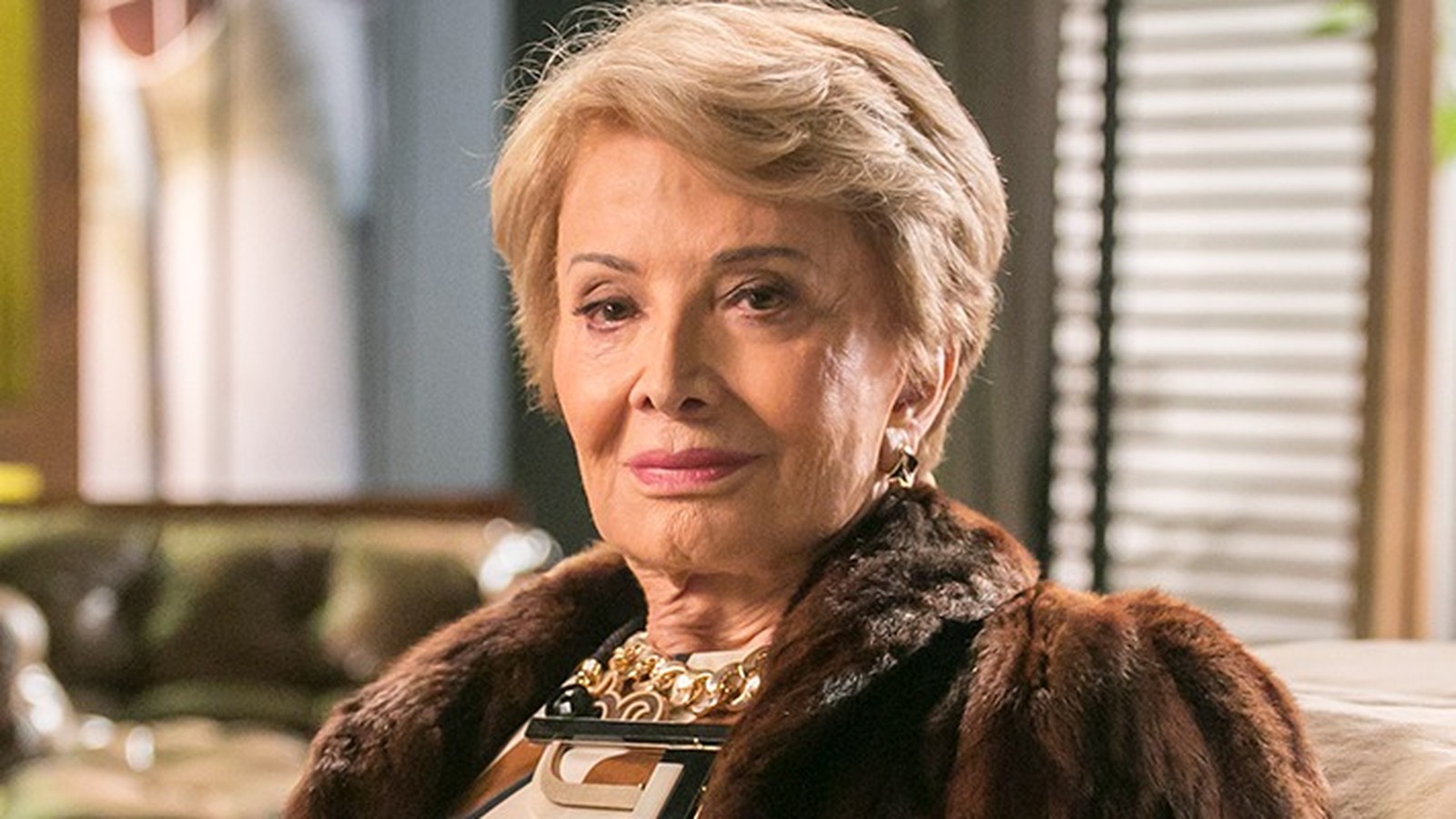 Close-up de Glória Menezes, mulher idosa, cabelo loiro, casaco de pele marrom, colar