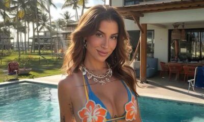 Bianca Andrade sorrindo em biquíni azul com colar, piscina e palmeiras ao fundo