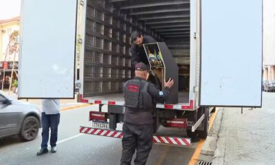Agentes do Ministério Público carregam máquina caça-níqueis em caminhão de apreensão na rua