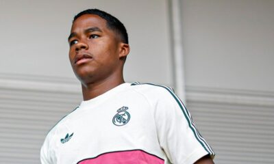 Jovem de pele escura com camisa branca do Real Madrid e Adidas olhando para o lado