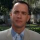 Tom Hanks como Forrest Gump, em terno claro, com expressão séria em parque