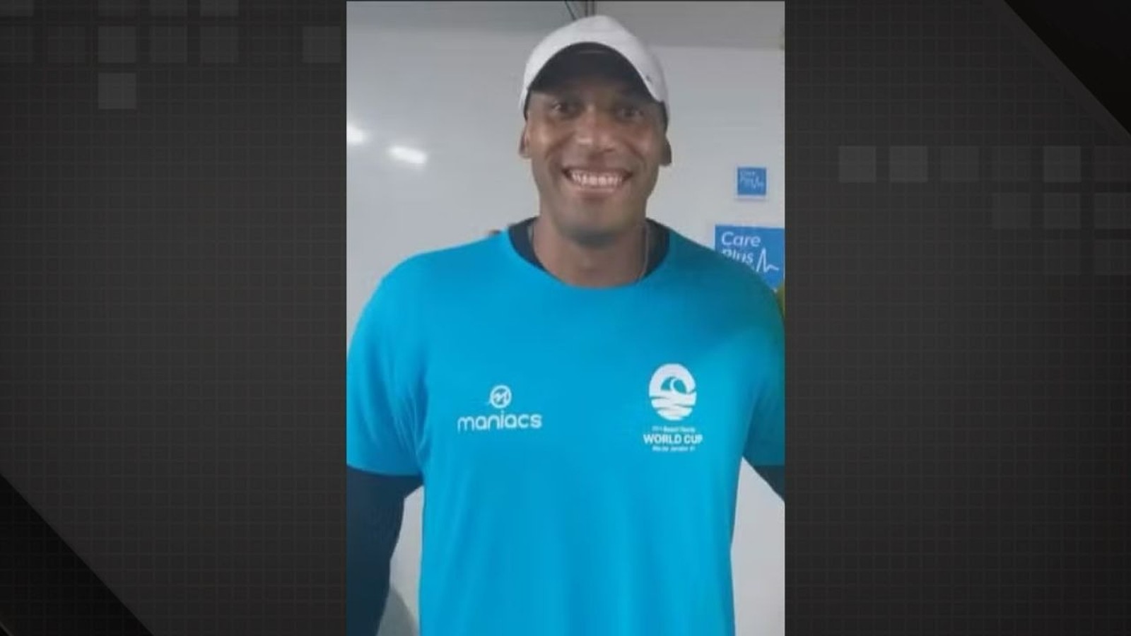 Professor Carlos Eduardo Cerqueira sorri com camiseta azul Maniacs World Cup e boné branco