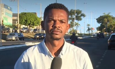 Repórter Kelven Melo com microfone em rua movimentada, com carros e prédios ao fundo