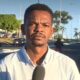 Repórter Kelven Melo com microfone em rua movimentada, com carros e prédios ao fundo