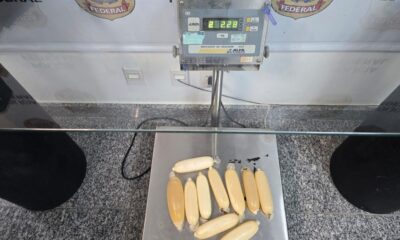 Pacotes de cocaína líquida em preservativos sobre balança digital marcando 2.28 kg e logo PF