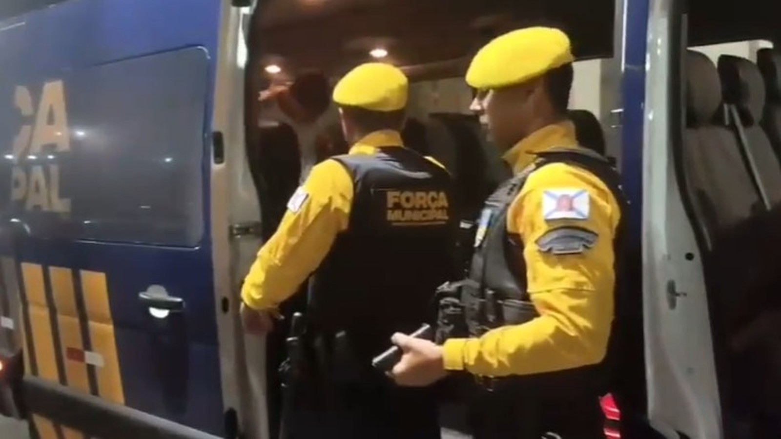 Agentes da Força Municipal com colete 'FORÇA MUNICIPAL' ao lado de van policial
