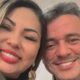 Selfie de uma mulher sorridente com batom vermelho ao lado de um homem sorrindo