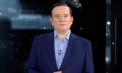 Jornalista Roberto Cabrini de terno azul e camisa em estúdio, olhando para frente