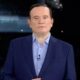 Jornalista Roberto Cabrini de terno azul e camisa em estúdio, olhando para frente