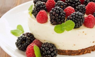 Cheesecake cremoso com amoras, framboesas e folhas de hortelã em um prato branco