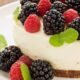 Cheesecake cremoso com amoras, framboesas e folhas de hortelã em um prato branco